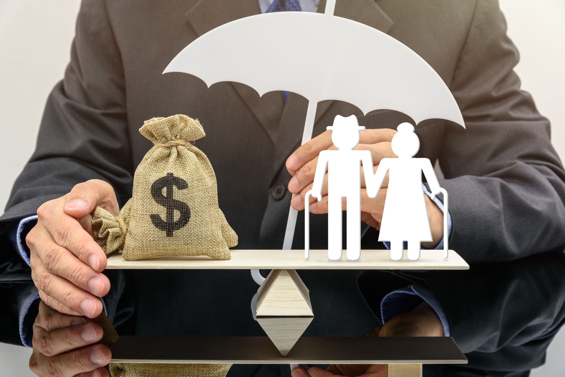 Seguro de pensiones para jubilados e impuesto a la seguridad social, concepto financiero : Pareja de ancianos o jubilados de edad avanzada se encuentra en un balancín o una balanza con una bolsa de dólares estadounidenses, bajo la protección de una aseg