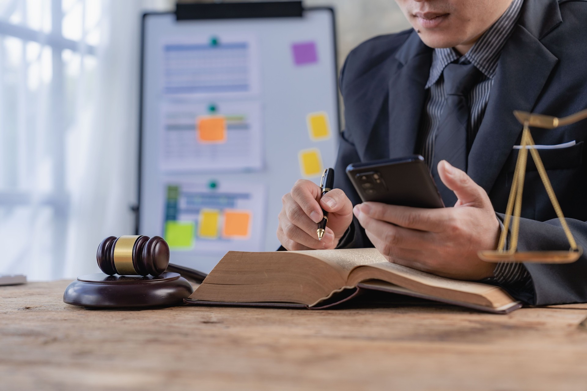 Abogado asiático que usa un teléfono inteligente para hablar con el cliente en el trabajo de consultoría con el icono del libro de derecho con escalas de oro Documentos y contratos Argumentos para las estrategias de defensa Lucha por la libertad