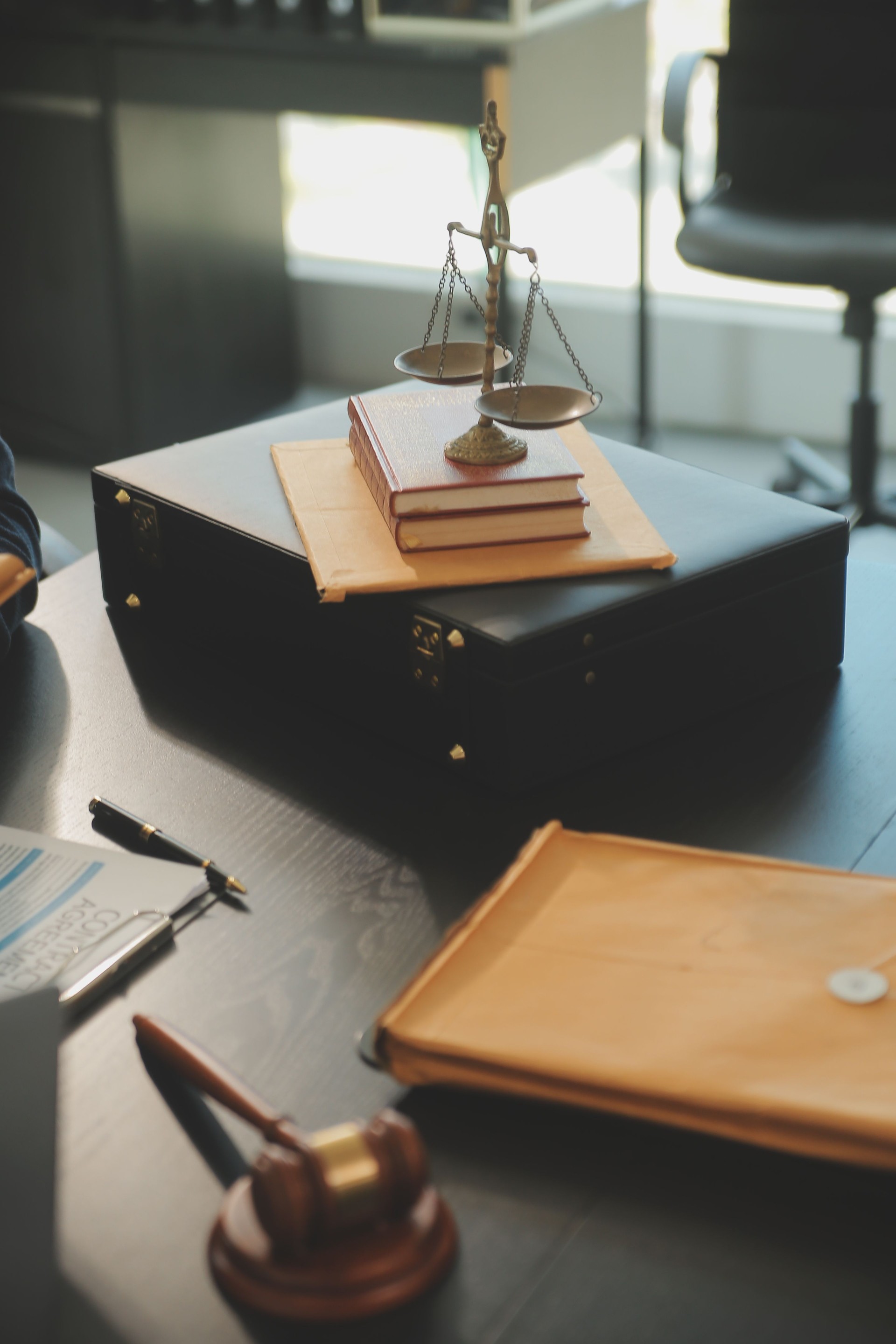 Justice and Law concept. Legal counsel presents to the client a signed contract with gavel and legal law or legal having team meeting at law firm in background